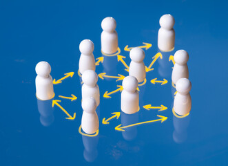 Wooden figures connected by glowing lines on a blue background representing networking and...