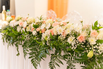 A stunning display of various flowers decorates a wedding reception table, enhancing the ambiance with shades of blush and white