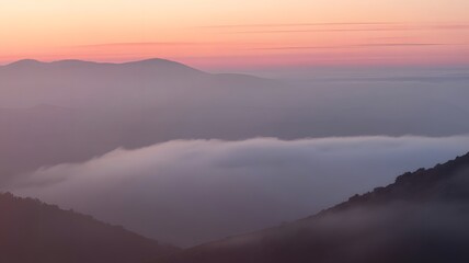 Fototapeta premium Serene mountain landscape at dawn with soft pink sky and a sea of clouds below
