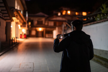 Man Taking Photo at Night in Traditional Japanese Street