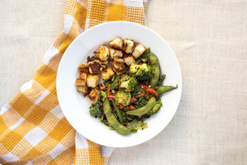 stir fried vegetables and edamame with pan grilled paneer, steamed broccoli,  healthy Vegetarian meal in a white ceramic plate