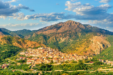 highland landscape of italian town between amazing green mountains with scenic sunset cloudy sky on background