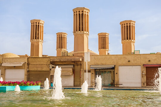 5 old towers-badgir or windcatchers in Amir Chakhmaq Square in Yazd, Iran. These are traditional cooling structures used since time immemorial in the East. Foreground is city fountain and flower bed