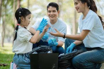 Happy Asian family collecting plastic bottles at the park.