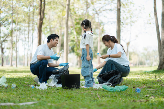 Happy Asian family collecting plastic bottles at the park.