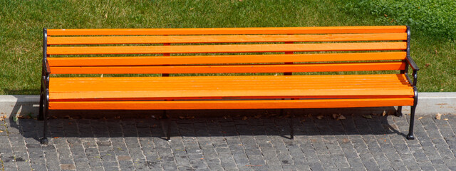 A long bench is sitting on a brick sidewalk