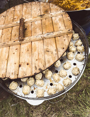 A large metal bowl with a wooden board on top of it. The bowl is filled with dumplings