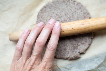 A person is actively rolling out dough using a wooden rolling pin
