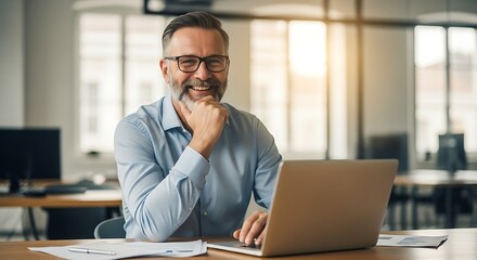 Smiling businessman in office working on laptop with glasses