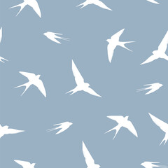 Vector seamless pattern with silhouettes of swallows soaring in the sky