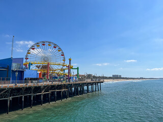 A pier with a Ferris wheel and a beach in the background