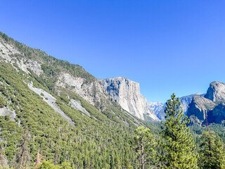 A mountain with a cliff face and a blue sky in the background