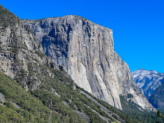 A mountain with a cliff face and a blue sky in the background
