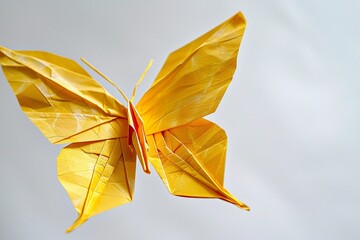 Delicate yellow origami butterfly showcasing intricate folds and craftsmanship against a bright background