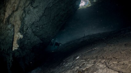 Sunlight streams into a dark, rocky cave, creating a dramatic contrast.