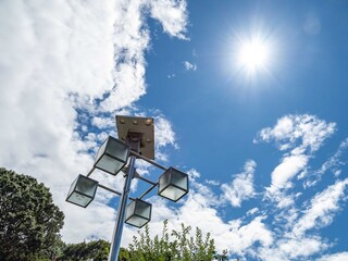 森の中の夏の雲と青い空と太陽に照らされるデザインされた照明塔に陽が透ける