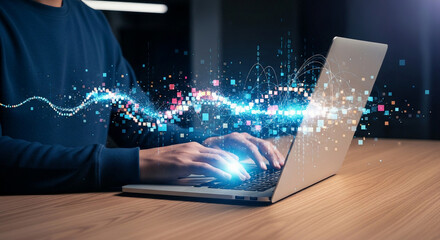 A person types on a laptop emitting blue digital light streaks on a wooden desk, creating a futuristic, focused, and technologically advanced ambiance.
