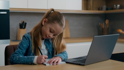 Caucasian daughter child kid girl schoolgirl pupil listen tutor online lesson course school distant learning class remote teacher writing at home kitchen studying with laptop video call e-learning