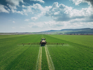 Aerial view of farming tractor plowing and spraying on field