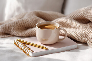 Time Management with Bullet Journal Layout. Cozy coffee cup on a notebook with a soft blanket in a serene setting.