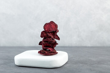 Balancing stack of Dried beet slices. Dehydrated, dried beetroot chips on white wooden board. Healthy vegan snacks