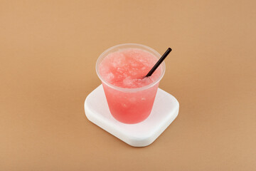 Flavored Shaved Ice or Frozen Pink Slushie Drink in disposable plastic cup. Grapefruit pomelo granizado. Refreshing summer fruit drink. Iced cocktail served with drinking straw