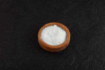 E551 Food additive. Powder of Colloidal silicon dioxide in wooden dish on black textured stone surface. Enterosorbent powder. Highly dispersed pyrogenic SiO2. Anti-caking agent