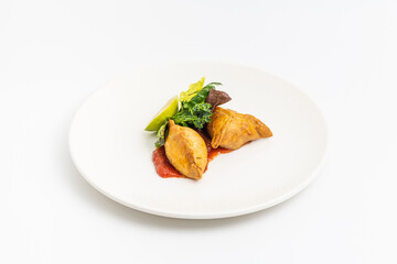 Meat empanadas on tomato sauce, served with fresh greens and lime wedge