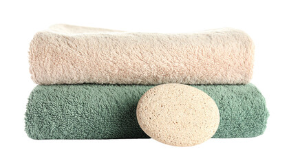 Stack of folded green and beige towels, a pumice stone isolated on solid background