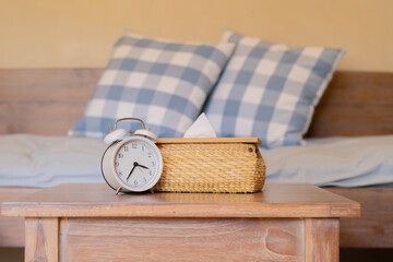 White vintage alarm clock with woven tissue box on wooden table in cozy living room