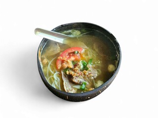 Top view of Indonesian style soup with beef, vegetables, and clear broth served in a black bowl on white background, highlighting local culinary tradition