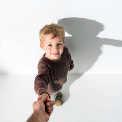 Child Reaching Out – Toddler Holding Parent’s Hand in Soft Light