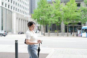 Two Korean women in their twenties in casual clothes walk along a boulevard sidewalk, talking and...