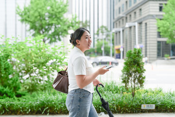 Two Korean women in their twenties in casual clothes walk along a boulevard sidewalk, talking and...
