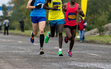 leaders race are european and two african athletes running marathon on wet road