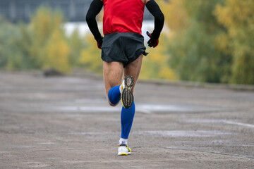 back view man running marathon in long sleeve and compression socks