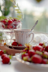 A delicate tea cup stands amongst fresh strawberries on a beautifully arranged table, inviting guests to enjoy a relaxing afternoon filled with delicious treats and refreshing company