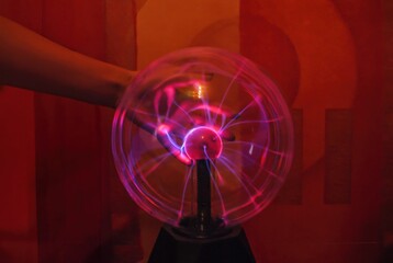 A woman's hand touches a plasma ball 