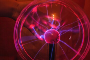 A woman's hand touches a plasma ball close-up