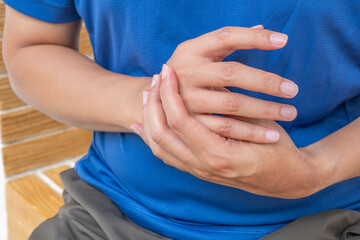 Asian man with palm pain after lifting heavy items during daily chores, in home setting. Ideal for...