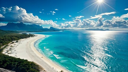 Bright sunlight illuminates a serene beach landscape with azure waters and distant mountains under a clear sky