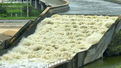 Drone shot of a canal draining water into the sea to reduce floods, storing fresh water and providing embankment support for road transport, ensuring balanced water and land resource management.
