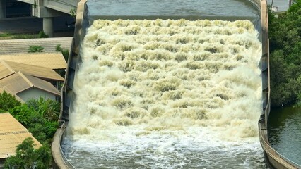 Aerial drone view of a canal draining water to the sea to prevent flooding, storing fresh water while supporting road transport on its embankment, aiding efficient water and land management.