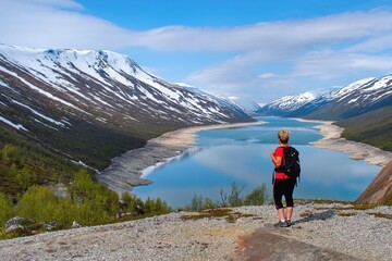Woman hiker watching beautiful scenery of mountail lake Raudalsvatnet in Norway