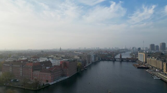 Aerial view of the Oberbaum Bridge spanning the River Spree, with red brick buildings lining the banks and city skyline in the distance, Berlin, Berlin, Germany.