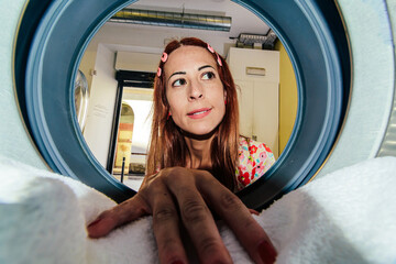 Housewife loading clothes into washing machine at laundromat