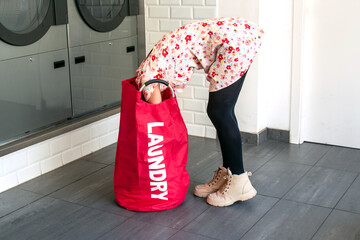 Girl looking inside laundry bag in a laundromat