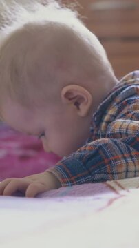 adorable little baby in checkered shirt nibbles plastic tube of medical nozzle suction at bed in light children room