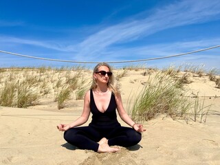 Woman doing yoga on a sandy beach, embracing a calm and natural lifestyle. Healthy aging,...