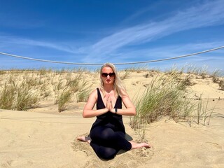 Woman doing yoga on a sandy beach, embracing a calm and natural lifestyle. Healthy aging,...